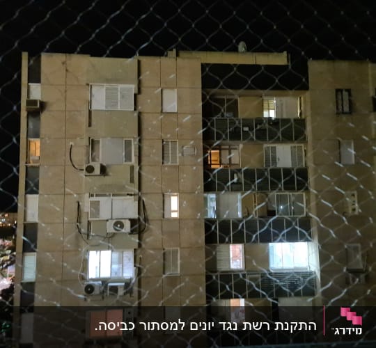 רשת מתכת מול בניין מגורים בלילה